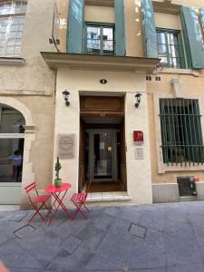 two red chairs and a table in front of a building at Hôtel l'Amphithéâtre in Nîmes