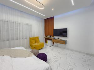 a bedroom with a tv and a yellow chair at Serenity Suite in Accra