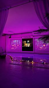 a purple room with a tv and a table with lights at Catalpa in Al Ḩārah