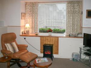 a living room with a chair and a table and a window at Bakehouse Cottage in Balnald