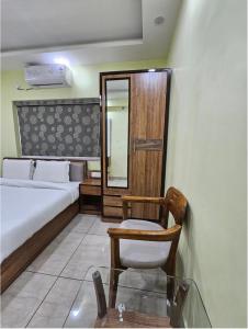 a bedroom with a bed and a chair and a mirror at V3 Inn Private Limited in kolkata