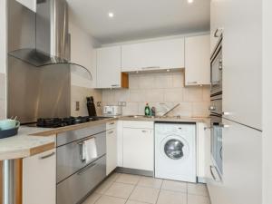 a kitchen with white cabinets and a washer and dryer at Reflections - Balcony Views of Poole Harbour in Poole