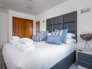 a bedroom with a large white bed with blue pillows at Reflections - Balcony Views of Poole Harbour in Poole