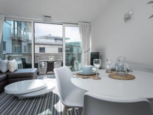 a white dining room with a white table and chairs at Reflections - Balcony Views of Poole Harbour in Poole
