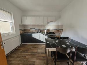 a kitchen with white cabinets and a black table at Casa Piatra Corbului in Gura Teghii