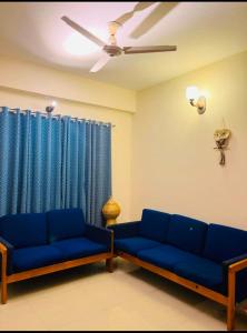 a living room with blue couches and a ceiling fan at Pakhir Basha in Dhaka