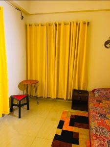 a living room with yellow curtains and a table at Pakhir Basha in Dhaka