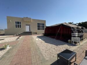 a house with a tent in front of it at January Rest in Sur