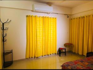 a bedroom with mustard yellow curtains and a bed at Pakhir Basha in Dhaka