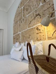 a bed with white pillows and a brick wall at F Home in Noto
