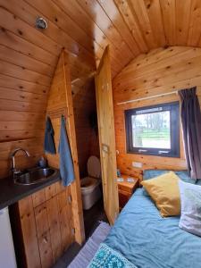ein Badezimmer mit Waschbecken und ein Bett in einer Blockhütte in der Unterkunft Swifterlodge in Kerkenveld
