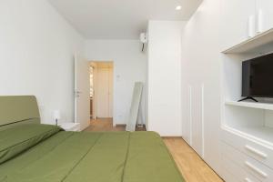 a bedroom with a green bed and a flat screen tv at House Tuscany in Poggibonsi