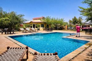 a man is cleaning a swimming pool with a mop at Meladin Sariska in Tehla