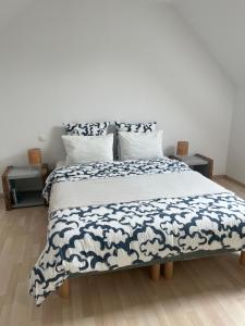 a large bed with a blue and white blanket on it at Le Petit Lavoir - Maison Cosy à Mayet in Mayet