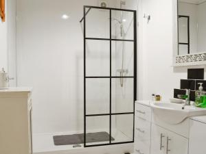a white bathroom with a shower and a sink at 5 Church Square in Rigg +7 photos