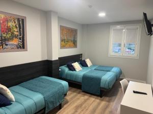 a room with two beds and a table at Pension San Anton in Melide