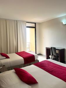 a hotel room with three beds with red pillows at Hotel arimaca in Ríohacha