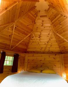 a bed in a wooden room with a ceiling at camping de brocéliande in Néant-sur-Yvel