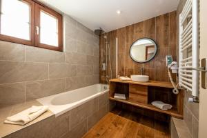 a bathroom with a tub and a sink and a mirror at The Originals Boutique, Hôtel La Ferme du Pape, Eguisheim in Eguisheim