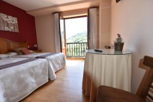 a bedroom with a bed and a table with a window at Hotel Restaurante Casa Petronila in Taramundi