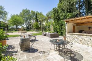 a patio with a table and chairs and a barrel at Domaine de Rhodes - 5 Chambres et 7 locations de vacances in Avignon