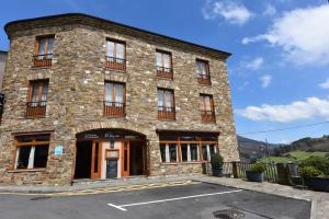 a large stone building with a parking lot in front at Hotel Restaurante Casa Petronila in Taramundi