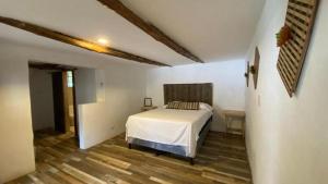a bedroom with a white bed and a wooden floor at Hot Chipilin El Paredon in Sipacate