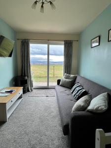 a living room with a couch and a large window at Black Isle Pods & Chalet in Allangrange Station