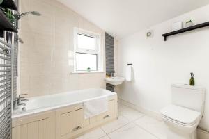 a bathroom with a tub and a toilet and a sink at NEW Spacious and Bright House-Parking-By FabAccommodation in Bristol