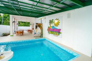 a house with a swimming pool with a sign on the wall at SunDay Hostel in Siquijor