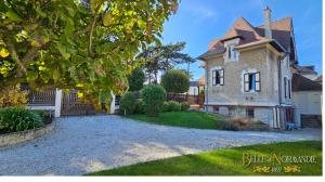 an old stone house with a fence in the yard at Belle de Normandie- Villa Balnéaire d'Exception - Plage au bout de la rue in Ouistreham