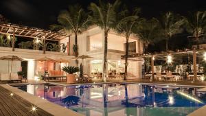 a swimming pool in front of a house at night at Hotel Maui Maresias in Maresias