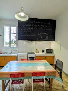a kitchen with a table with chairs and a chalkboard on the wall at White Chapel in Condom