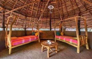 two beds in a thatched room with a table at Galoya Cool Cool Hotel in Ampara