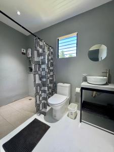a bathroom with a toilet and a shower curtain at Siqui Pods in Siquijor