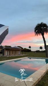 a swimming pool with a palm tree and a house at Cabaña La Conquista in Goya
