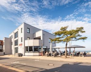 a building with people sitting at tables outside of it at Ostsee Suite 3 - Strandperle in Niendorf