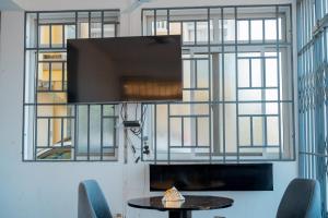 a room with a tv and a table and windows at Mach Hotel in Dar es Salaam
