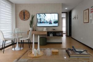 a living room with a table and a tv on the wall at Like a Home - 2Bedrooms - QueenBed - Balcony - Parking - 7Th FLOOR in Quito