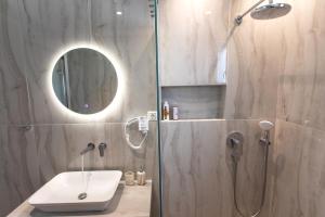 a bathroom with a shower with a sink and a mirror at ANAX APARTMENTS PARGA in Parga +74 photos
