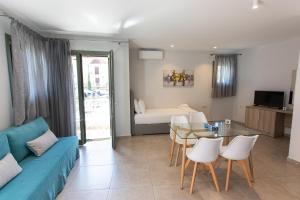 a living room with a blue couch and a glass table at ANAX APARTMENTS PARGA in Parga