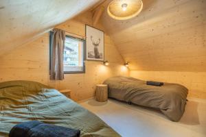 a bedroom with two beds in a wooden cabin at Chalet Cocooning avec SPA Les Granges de Thuy in Thônes