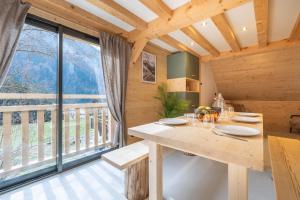 a dining room with a table and a large window at Chalet Cocooning avec SPA Les Granges de Thuy in Thônes