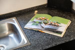 a kitchen counter with a sink and a book and a plate of food at Refugio do Outeiro - by Smarthomes in São Martinho do Porto +23 photos