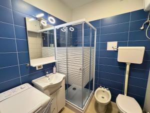 a blue tiled bathroom with a toilet and a sink at Villa Manuela in Grado +12 photos