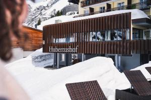 a person standing in the snow in front of a building at Wohlfühlhotel Hubertushof am Arlberg - Ski-In & Ski-Out - Sky Pool in Stuben am Arlberg
