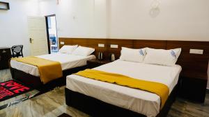 a hotel room with two beds with yellow and white sheets at Eettickal Homes in Ūdumbanshola