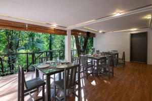 a dining room with tables and chairs on a balcony at Leopard Eye Resort in Kitulgala