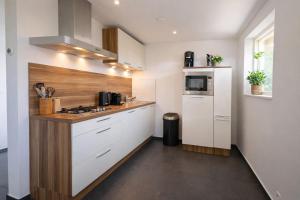 a kitchen with white cabinets and a stove top oven at Ballumerhoeve Tree Lodge in Ballum
