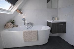 a white bathroom with a tub and a sink at Ballumerhoeve Tree Lodge in Ballum +7 photos